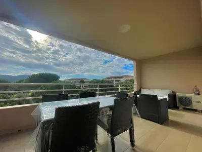 a balcony with a table and chairs and a large window at Appartement Résidence Salin Bay in Porto-Vecchio