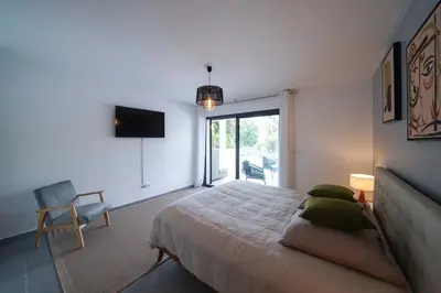 a bedroom with a bed and a television and a chair at Très belle villa à Ghisonaccia avec piscine chauffée in Ghisonaccia