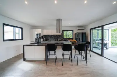 a kitchen with a island with black chairs in it at Très belle villa à Ghisonaccia avec piscine chauffée in Ghisonaccia