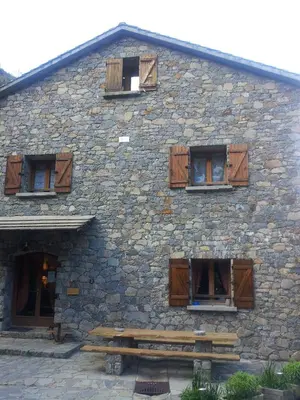 a stone building with wooden windows and a bench at Chambre d'Hôte 
