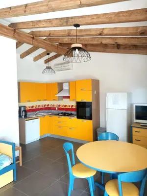 a kitchen with yellow cabinets and a table and chairs at Résidence Cantu di Mare in Olmeto