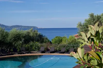 a swimming pool with chairs and the ocean in the background at Résidence Cantu di Mare in Olmeto