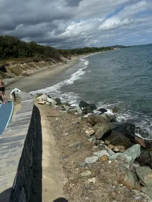 a person standing on a wall near the beach at Charmant appartement dans résidence avec piscines in Santa-Maria-Poggio