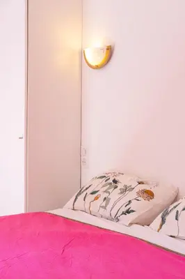 a bed with a pink blanket and a light on a wall at CASA MONICA CARGESE - Roseroom - Chambre d hote in Cargèse