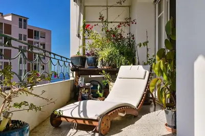 a chair on a balcony with potted plants on it at Appartement vue mer aux sanguinaires - stationnement et ascenseur in Ajaccio