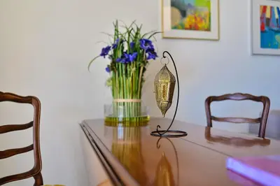 a glass table with a vase of flowers and a lamp at Appartement vue mer aux sanguinaires - stationnement et ascenseur in Ajaccio