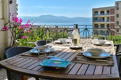 a wooden table with a bottle of wine and glasses at Appartement vue mer aux sanguinaires - stationnement et ascenseur in Ajaccio