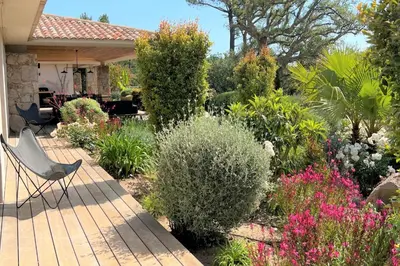 a garden with a chair on a wooden deck at Villa Pignotulli Di Cirendinu in Sainte-Lucie de Porto-Vecchio