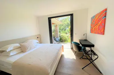 a bedroom with a bed and a desk and a window at Villa Pignotulli Di Cirendinu in Sainte-Lucie de Porto-Vecchio