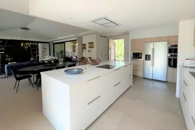 a kitchen with white cabinets and a dining room at Villa Pignotulli Di Cirendinu in Sainte-Lucie de Porto-Vecchio