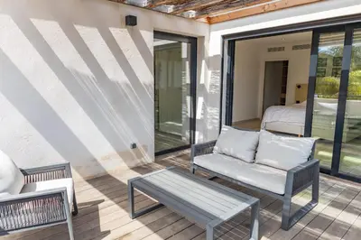 a porch with a chair and a bench and a bed at Villa Caipirinha Di Arasu in Sainte-Lucie de Porto-Vecchio