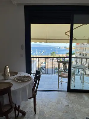a room with a table and a view of a balcony at Appartement Ajaccio vue mer in Ajaccio