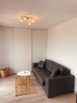 a living room with a black couch and a table at Grand studio toit terrase Ajaccio in Ajaccio