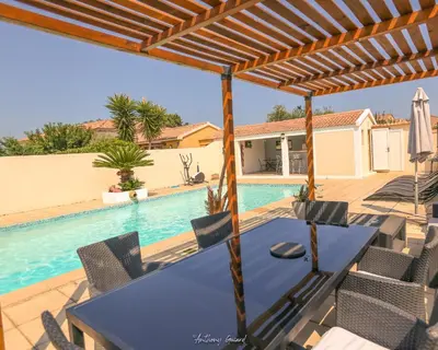 a patio with a table and chairs and a swimming pool at Résidence MARI in Folelli