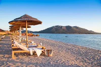 a beach with chairs and an umbrella and the water at La Plage Casadelmar in Porto-Vecchio