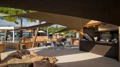 a building with a patio with tables and chairs at La Plage Casadelmar in Porto-Vecchio
