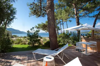 a patio with chairs and a table and an umbrella at La Plage Casadelmar in Porto-Vecchio