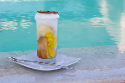 a drink in a bottle on a plate next to a pool at La Plage Casadelmar in Porto-Vecchio