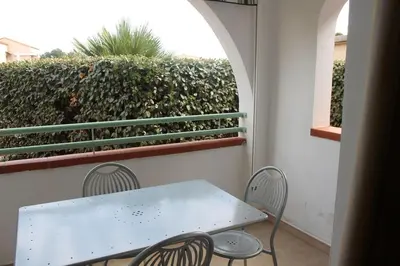 a white table and chairs on a balcony with a hedge at Grazioso bilocale a 200 m dal mare in residence con piscina e WI-FI in Linguizzetta