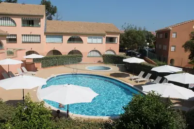 a pool with umbrellas and chairs and a building at Grazioso bilocale a 200 m dal mare in residence con piscina e WI-FI in Linguizzetta
