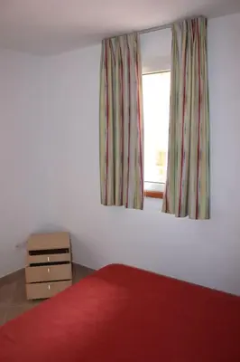 a bedroom with a red bed and a window at Grazioso bilocale a 200 m dal mare in residence con piscina e WI-FI in Linguizzetta