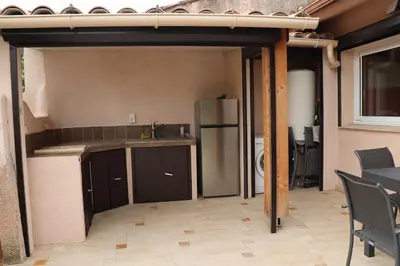 a kitchen with a refrigerator and a table and chairs at maison climatisée 150 m de la mer in Santa-Maria-Poggio