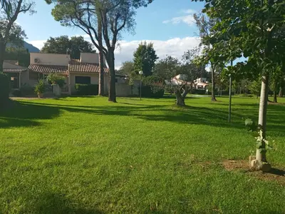 a yard with green grass and a house at maison climatisée 150 m de la mer in Santa-Maria-Poggio