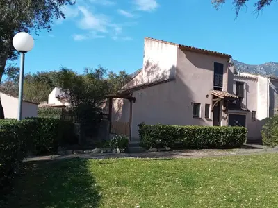 a large white house with a green yard at maison climatisée 150 m de la mer in Santa-Maria-Poggio