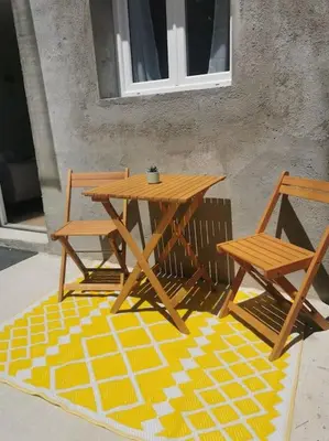 a wooden picnic table and two chairs on a rug at Appartement de 30m2 pour 2 personnes Venaco in Venaco