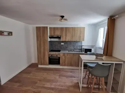 a kitchen with wooden cabinets and a table with chairs at Appartement de 30m2 pour 2 personnes Venaco in Venaco