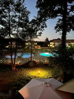a table with an umbrella in front of a pool at Villa avec terrasse et vue piscine, proche plage in Moriani Plage