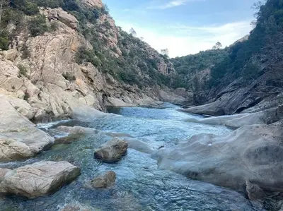 a river in a canyon with rocks in the water at Villa avec terrasse et vue piscine, proche plage in Moriani Plage