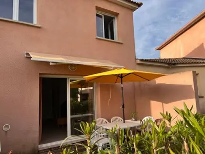 a table with a yellow umbrella and chairs in front of a building at Villa avec terrasse et vue piscine, proche plage in Moriani Plage