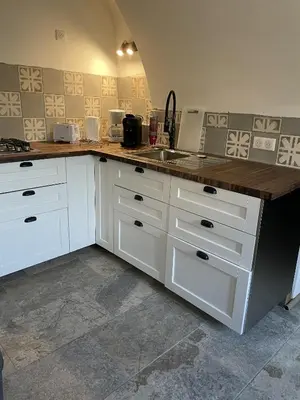 a kitchen with white cabinets and a wooden counter top at The Charming House in Ville-di-Paraso