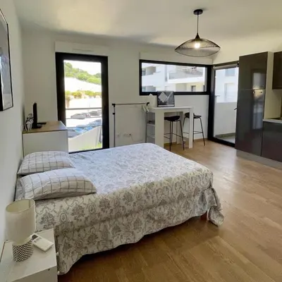 a bedroom with a large bed and a desk with a computer at Parking gratuit grande terrasse Proche Centre Ville in Ajaccio