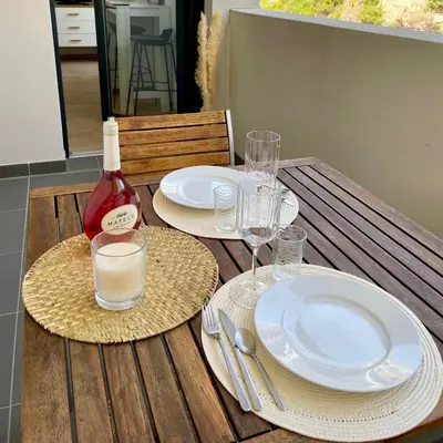 a table with plates and glasses and a bottle of wine at Parking gratuit grande terrasse Proche Centre Ville in Ajaccio
