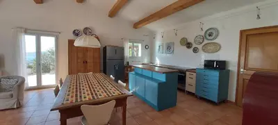 a kitchen with blue cabinets and a table in it at Maison Maquis - la vue, le silence, la mer in Tizzano