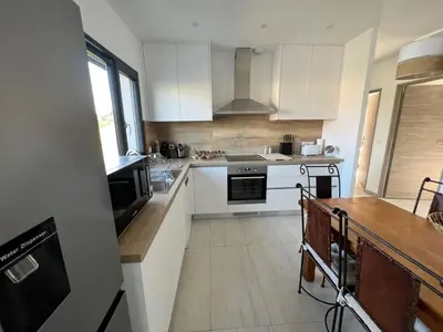 a kitchen with white cabinets and a wooden table at Casa Lamaghjone - Villa T4 avec piscine chauffée à 3,5km de la mer in Aléria
