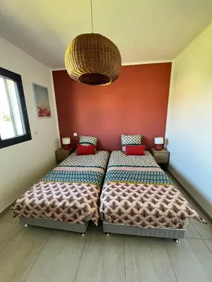 a bedroom with two beds and a chandelier at Casa Lamaghjone - Villa T4 avec piscine chauffée à 3,5km de la mer in Aléria