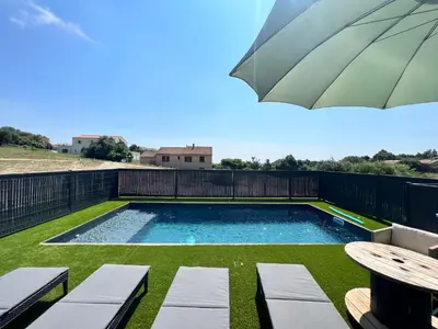 a swimming pool with a table and an umbrella at Casa Lamaghjone - Villa T4 avec piscine chauffée à 3,5km de la mer in Aléria