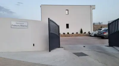 a white building with a gate in a parking lot at Palazzu B reservation 3 nuits minimum in Ajaccio