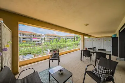 a balcony with chairs and tables and a large window at Grand T2 terrasse 27m2 plein sud Folelli centre in Folelli