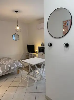 a room with a table and a bed and a table and a mirror at T1 Centre ville Carré d'or proche plage in Ajaccio
