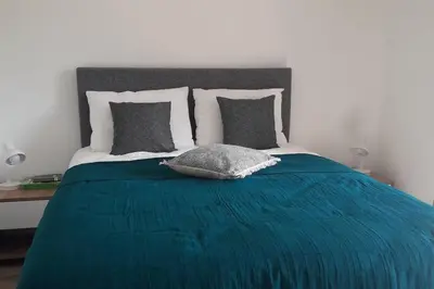 a bed with a blue blanket and pillows on it at Très joli appartement T3 fraîchement rénové, dans résidence hôtellière in Lecci