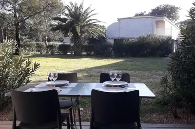 a table with chairs and wine glasses on a patio at Très joli appartement T3 fraîchement rénové, dans résidence hôtellière in Lecci