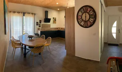 a dining room with a table and a clock on the wall at CASA JEANATA in Sainte-Lucie de Porto-Vecchio