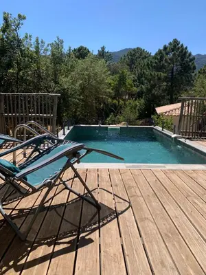 a deck with a chair next to a swimming pool at CASA JEANATA in Sainte-Lucie de Porto-Vecchio