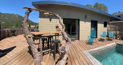 a house with a wooden deck with a table and a pool at CASA JEANATA in Sainte-Lucie de Porto-Vecchio