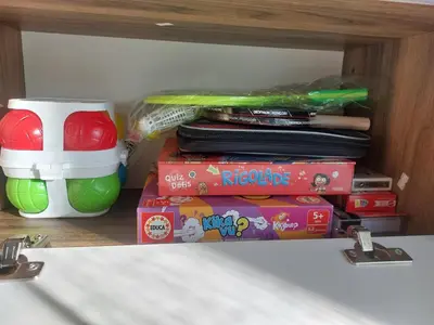 a shelf with a stack of books and a toy container at NOUVEL LOCATION d'un Bel appart T2 climatisé et meublé au RDCh avec piscine dans residence les Melody in Santa-Maria-Poggio