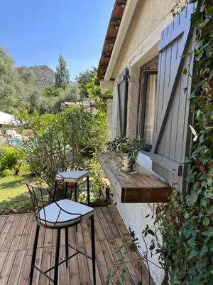a wooden deck with two chairs and a window at L’oléado in Oletta